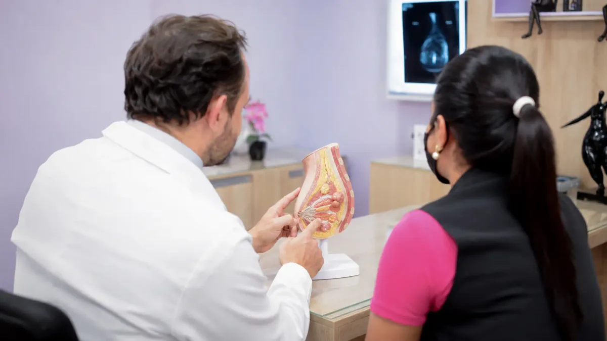 Mastologista explica a anatomia da mama em modelo anatômico durante consulta, na Clínica Preciore